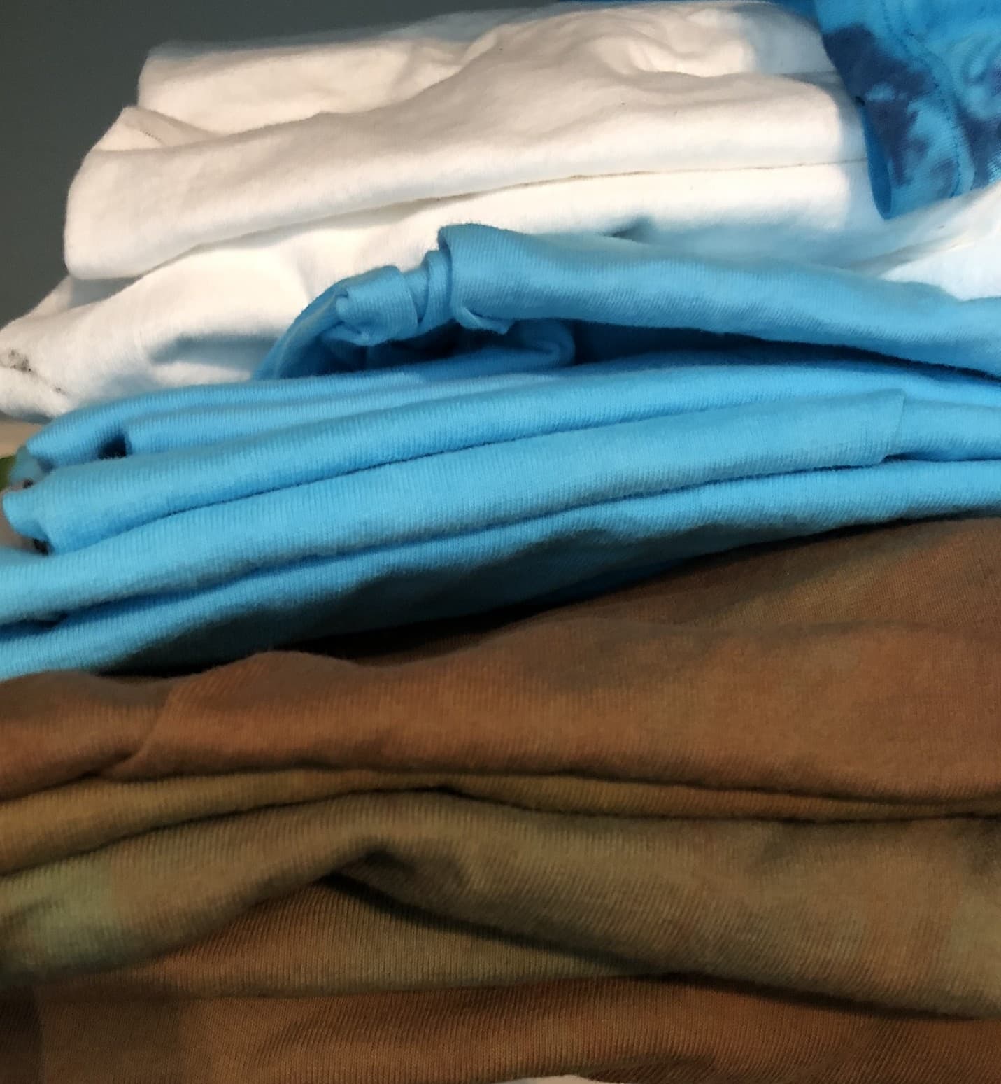 Stack of folded, earthy colored t-shirts, the finished product