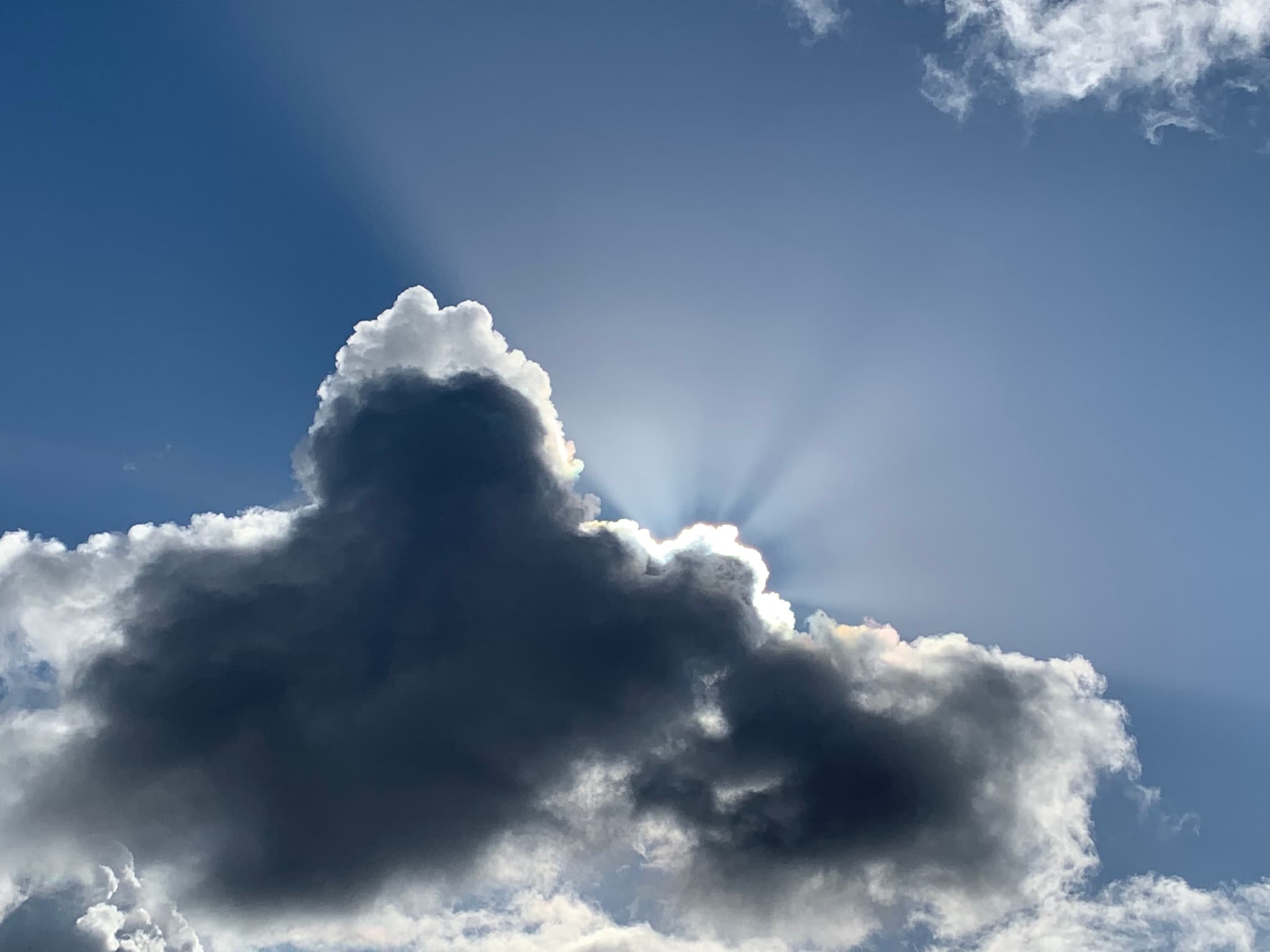 Sunrays breaking from behind a dark storm cloud — the visual essence of Sun & Rain