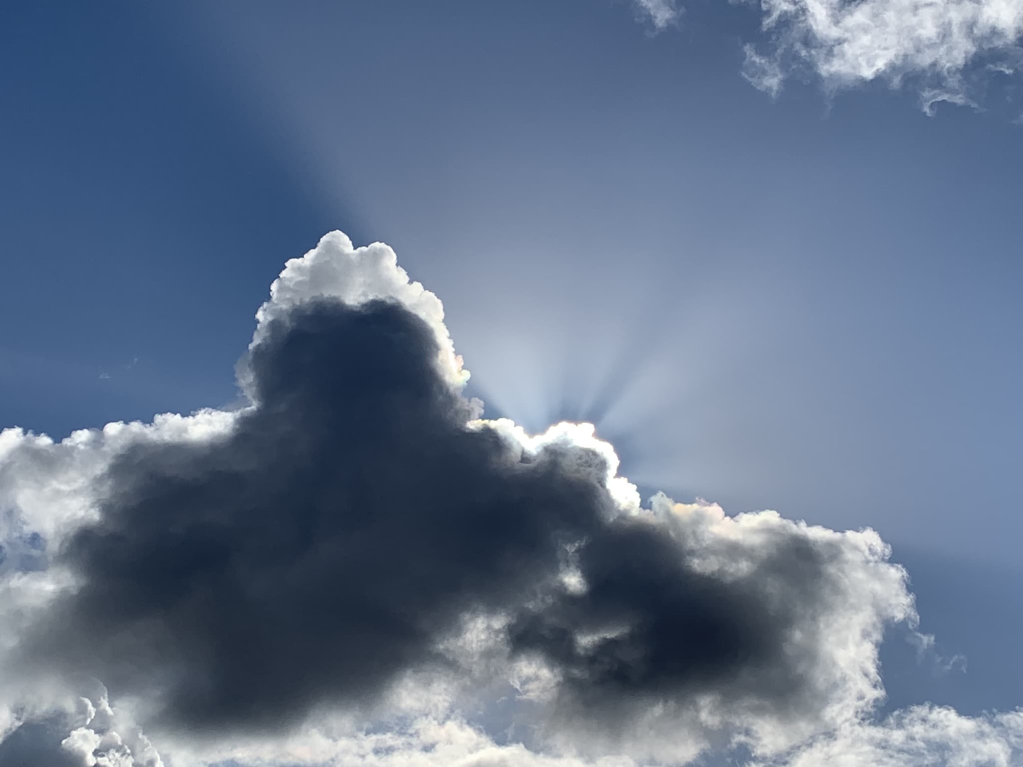 Sunrays breaking from behind a dark storm cloud, the visual essence of Sun & Rain